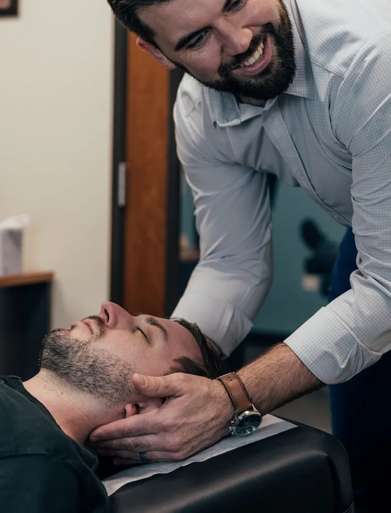 Dr. Brent Johnson smiling while adjusting a patient's neck