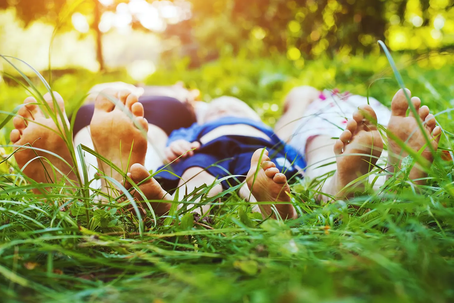 Children lying barefoot in the grass on a sunny day
